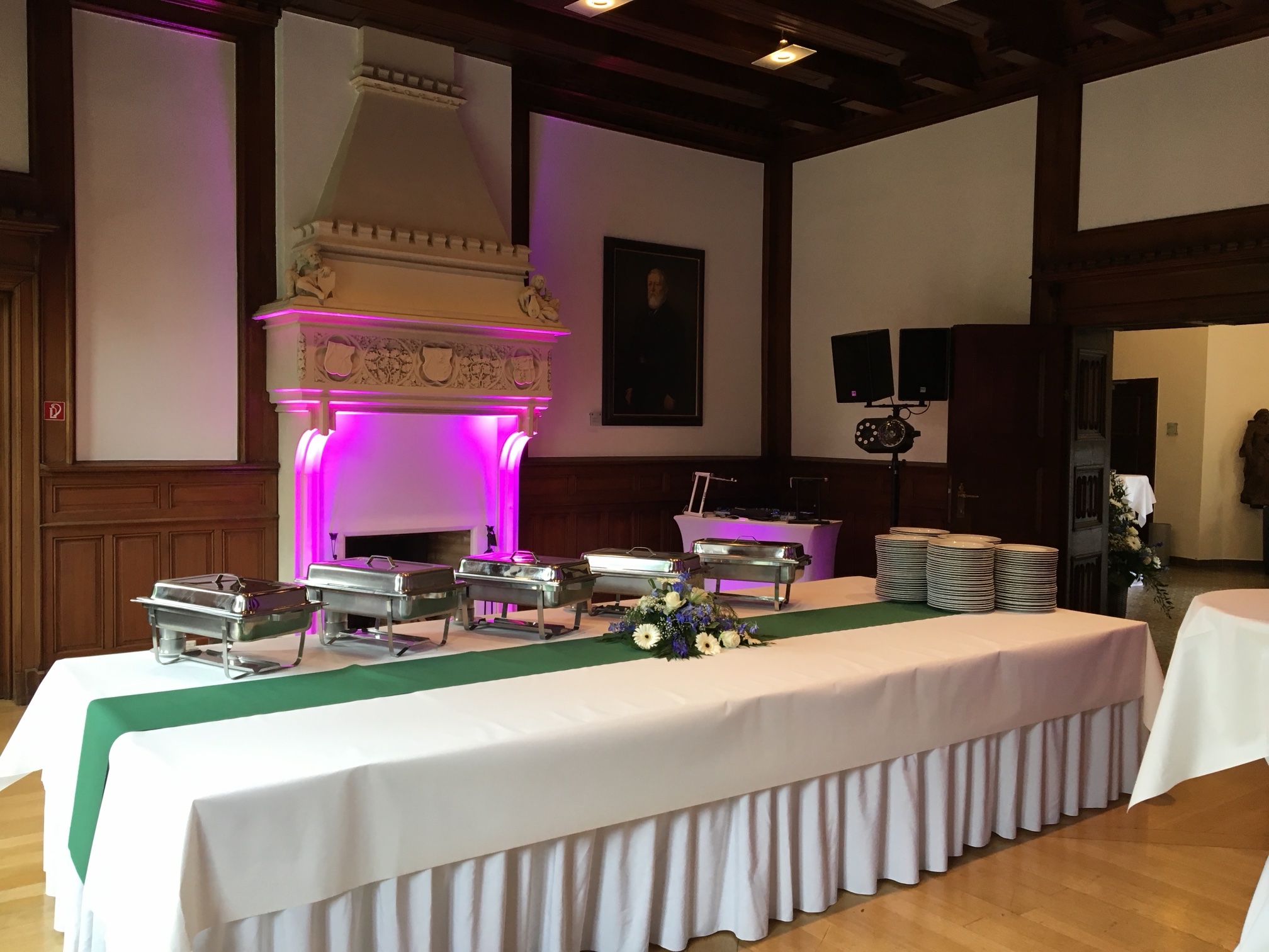 Kaminsaal auf Schloss Paffendorf mit Buffet und DJ-Pult im Hintergrund, farbiges Licht am Kamin