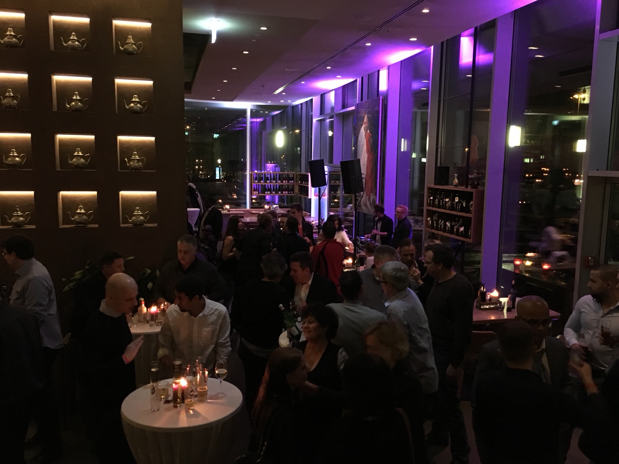Innenraum des bona'me in Köln mit violettem Licht, Wanddeko und DJ-Pult im Hintergrund