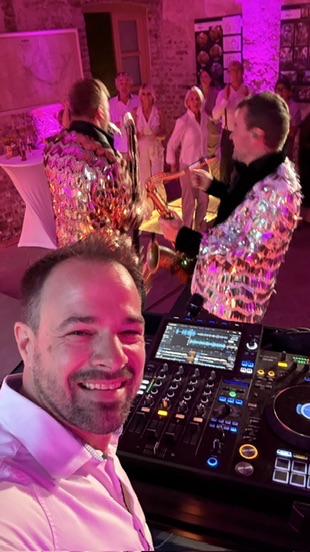 René Braun am Pult, dahinter zwei Saxophonisten in Glitzerjacken