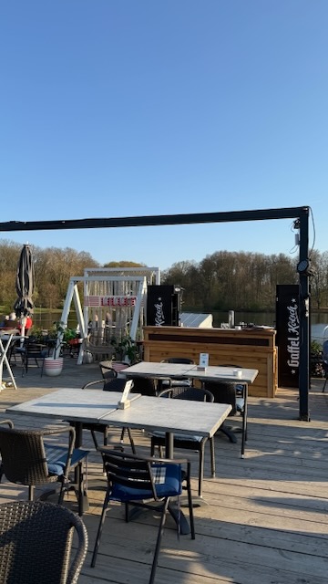Terrasse des Haus am See in der Abendsonne mit Stehtischen und Blick über den See